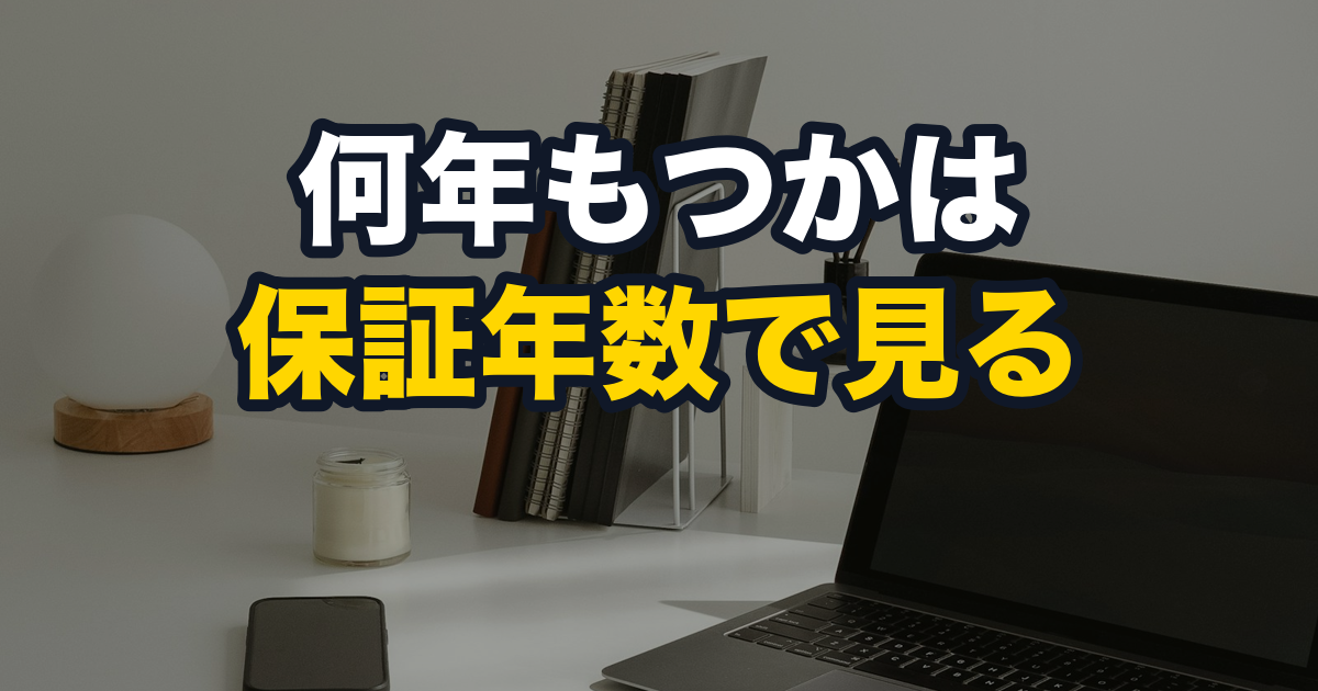 白い机の上に置かれたノートパソコンと、立てた数冊のノート
